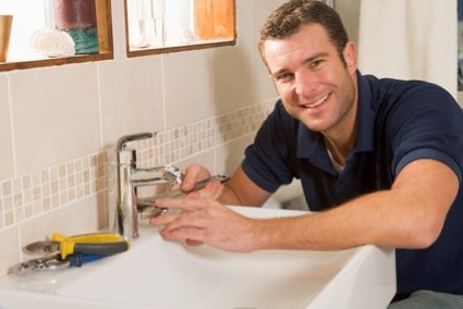 Local Plumber working on sink smiling